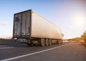 Ciężarówka poruszająca się z dużą prędkością po autostradzie podczas ładnej pogody późnym popołudniem.